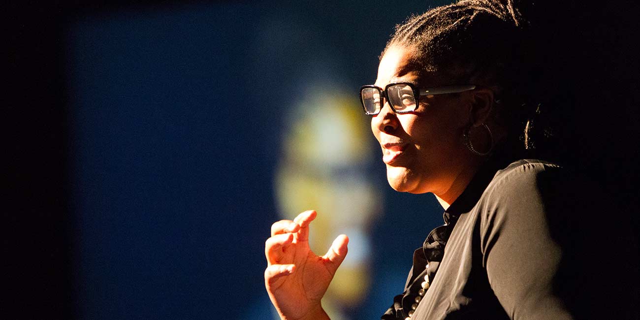 A dynamically lit photo of a female speaker at an WLC event