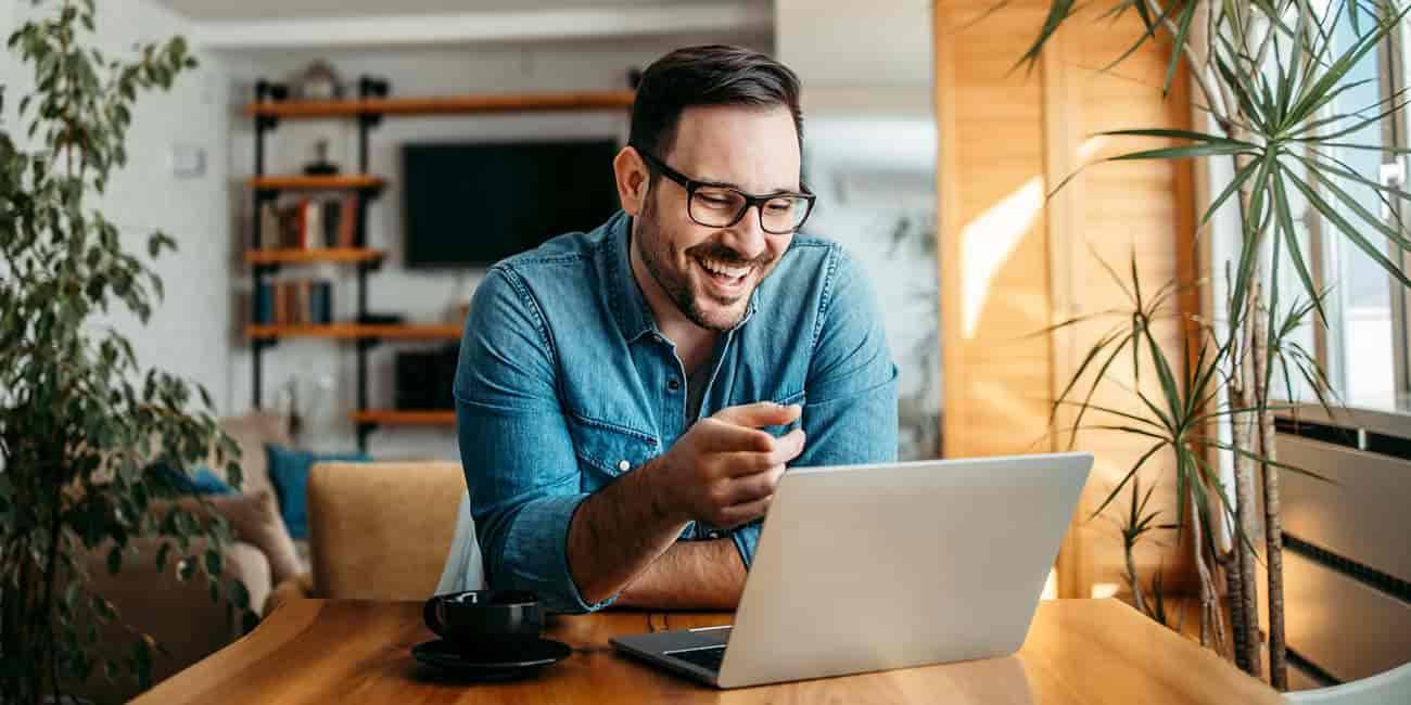 A happy middle aged male smiles and interacts with his laptop computer