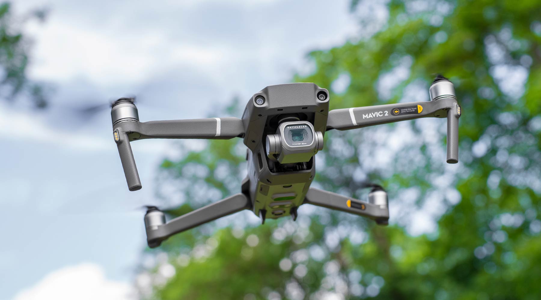 A drone flies through an open clearing on a blue sky with a camera built in