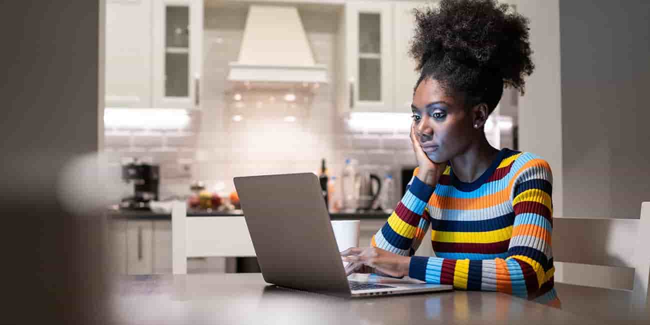 A young women reads email at home on a laptop