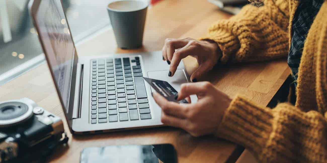 A person holds a credit card as they navigate a laptop while sitting at a nice desk